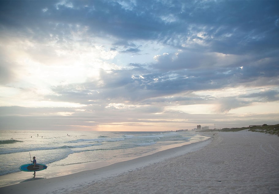 Destin Florida Outdoor Activities person on the beach holding surfboard on destin florida beach